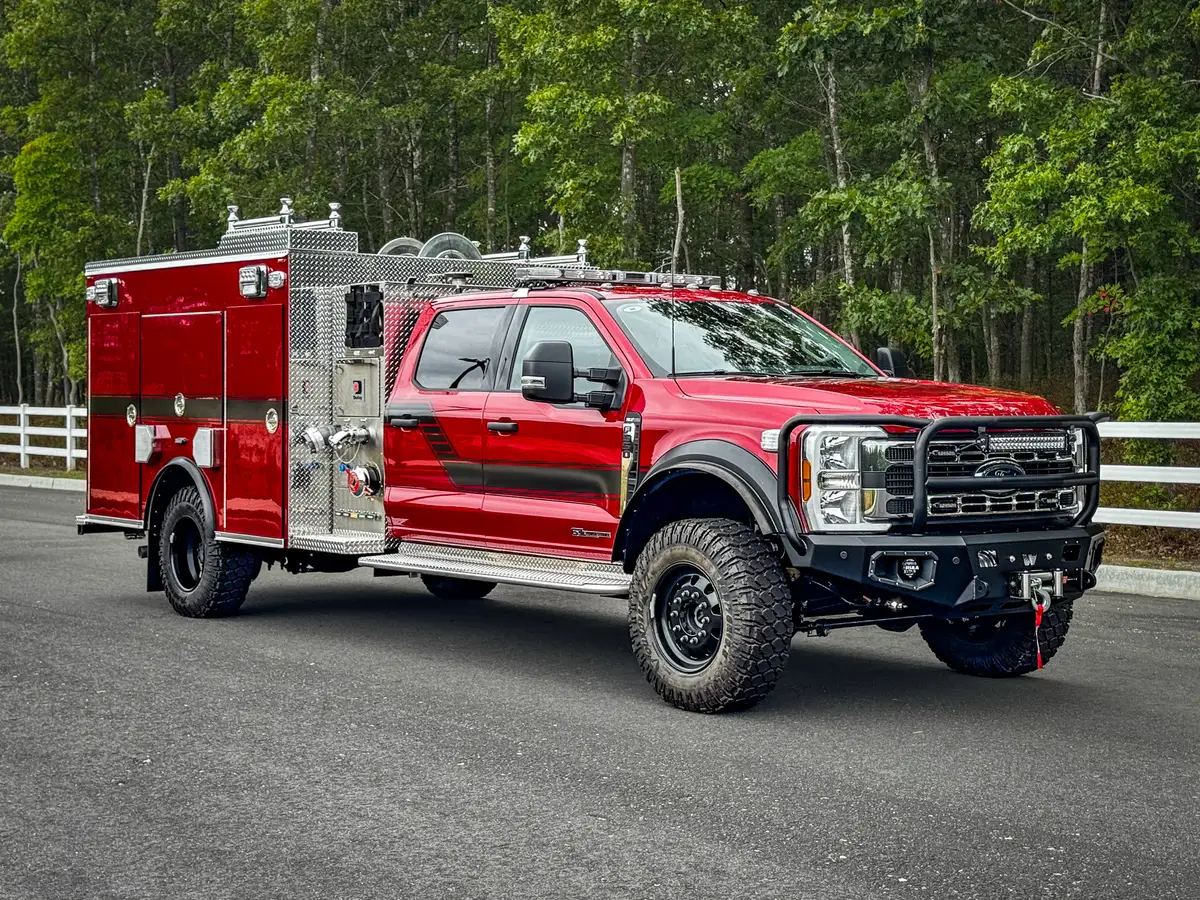 Front-left exterior view showing cab, body compartments, and heavy-duty front bumper.